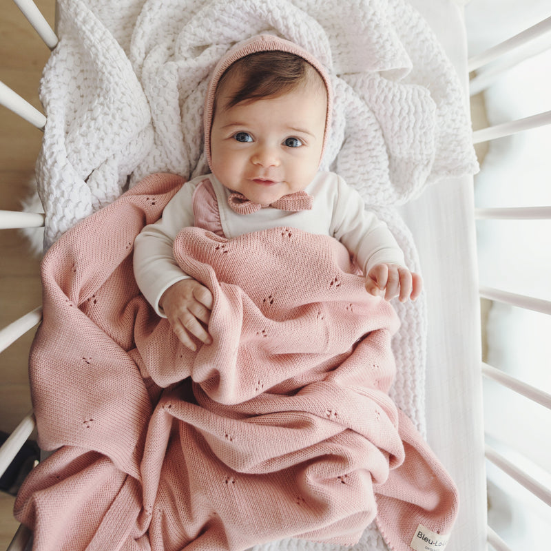 Baby lying on Bleu La La Organic Pointelle Luxury Knit Swaddle Blanket in ballet slipper with lightweight pointelle knit detail.