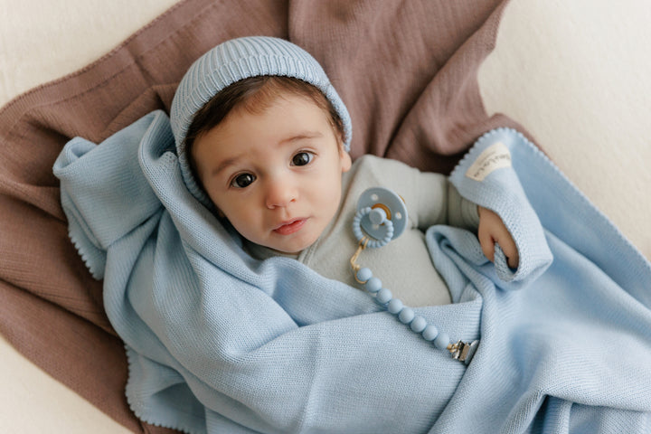 Infant wrapped in a light blue Bleu La La organic cotton luxe baby blanket, cozy knit for naps and cuddles