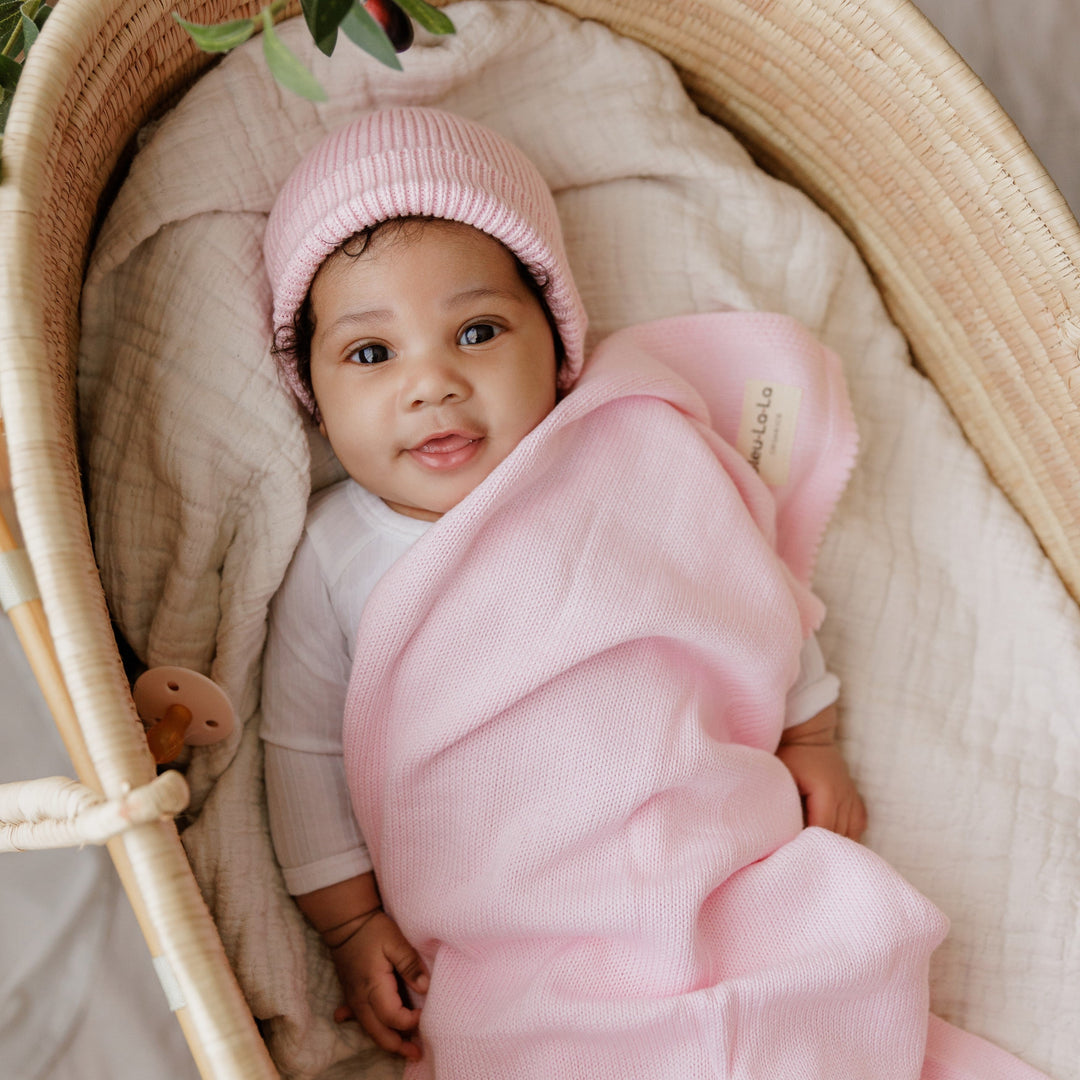 Baby in a basket wrapped in a Bleu La La pink organic knit blanket, soft luxe newborn swaddle style