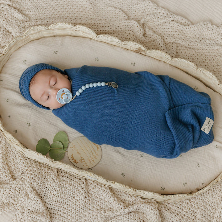 Newborn swaddled in a Bleu La La navy organic knit blanket, cozy sleep-ready baby wrap