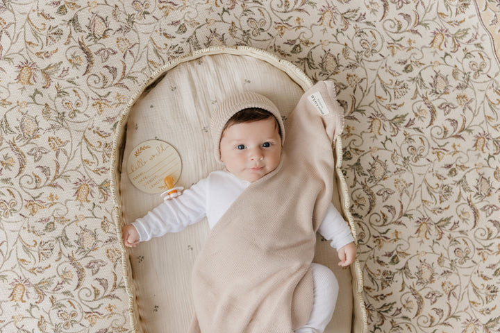 Newborn resting in a Bleu La La beige organic knit blanket, soft cotton comfort