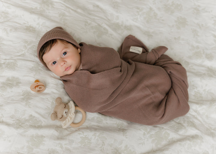 Baby swaddled in a Bleu La La brown organic knit blanket, cozy everyday newborn essential