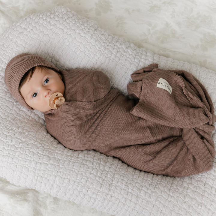 Newborn in a Bleu La La brown organic knit blanket on a textured blanket, cozy cotton feel