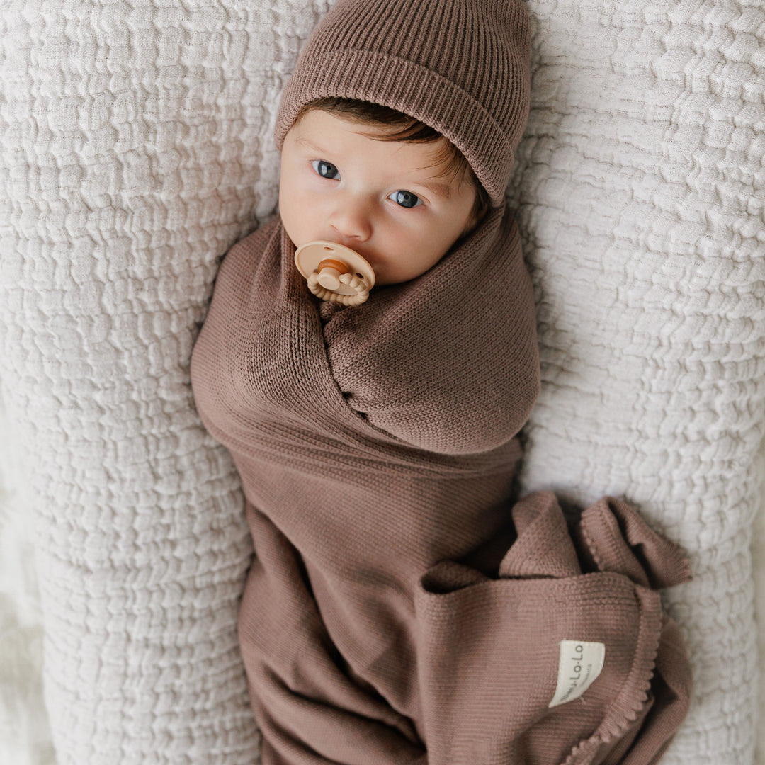 Baby wrapped in a Bleu La La brown organic knit blanket, cozy newborn swaddle look