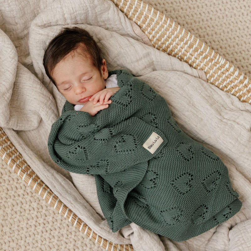 Sleeping baby swaddled in Bleu La La 100% Cotton Luxury Knit Heart Swaddle Baby Blanket in hunter green with lightweight knit warmth.
