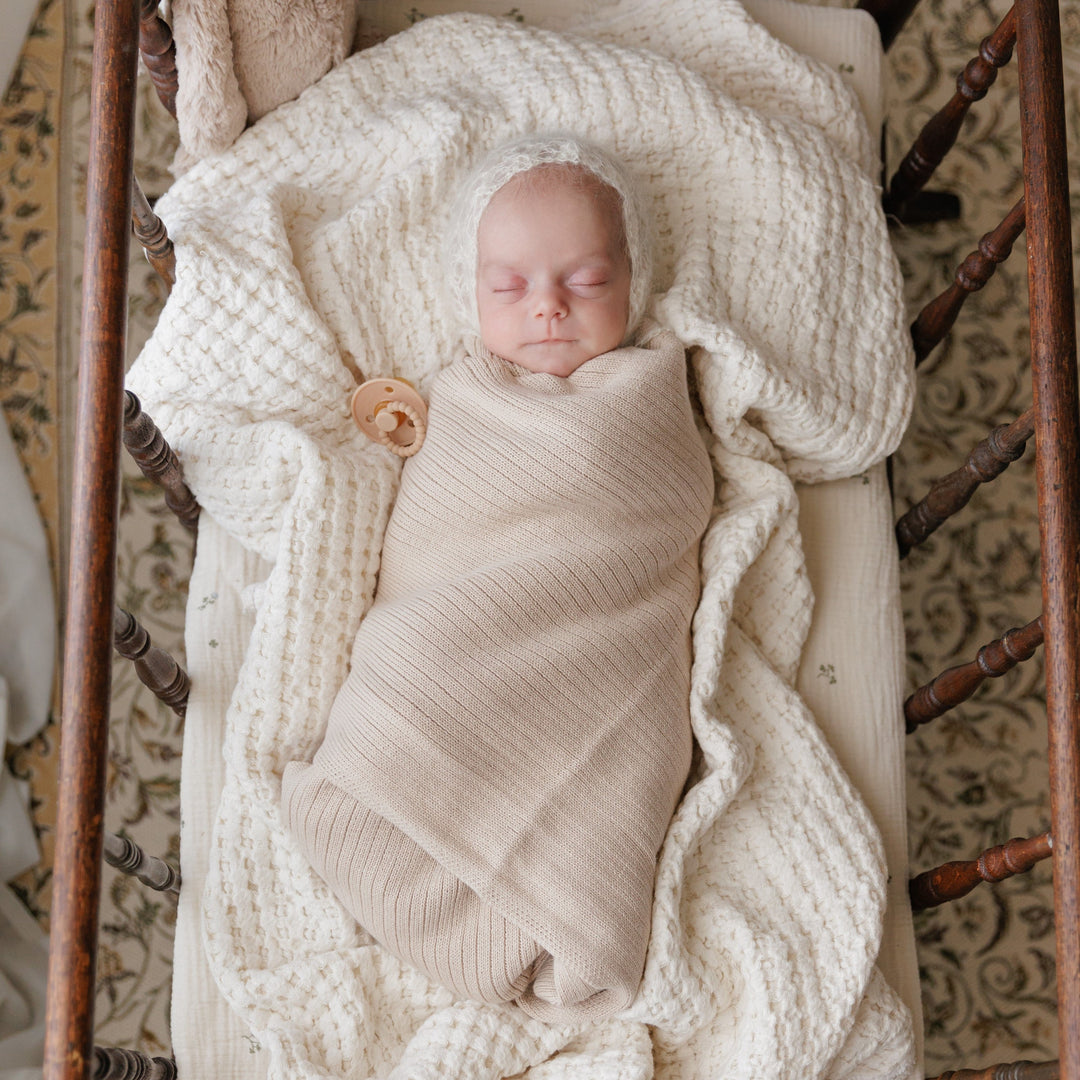 Two babies wrapped in Pink Bleu La La Organic Ribbed Knit Cotton Baby Blankets on neutral bedding, soft knitted pink baby swaddle blankets
