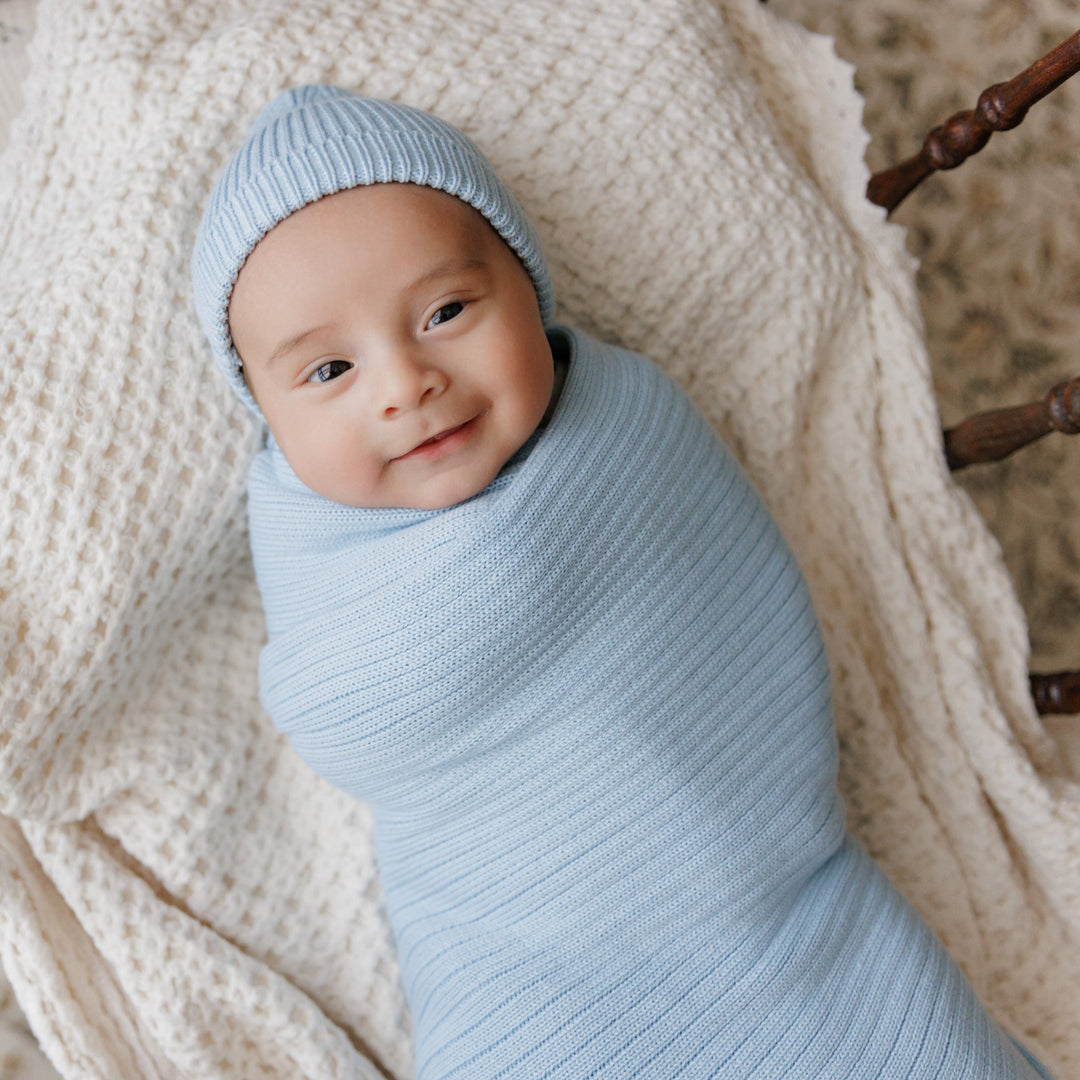 Baby wrapped in Bleu La La Organic Ribbed Knit Cotton Baby Blanket in light blue, ribbed organic cotton swaddle for newborns