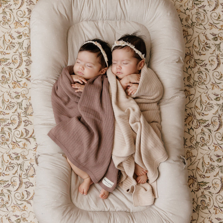 Newborn twins wrapped in Bleu La La Organic Ribbed Knit Cotton Baby Blankets in blush pink and beige, cozy ribbed swaddle blankets for infants