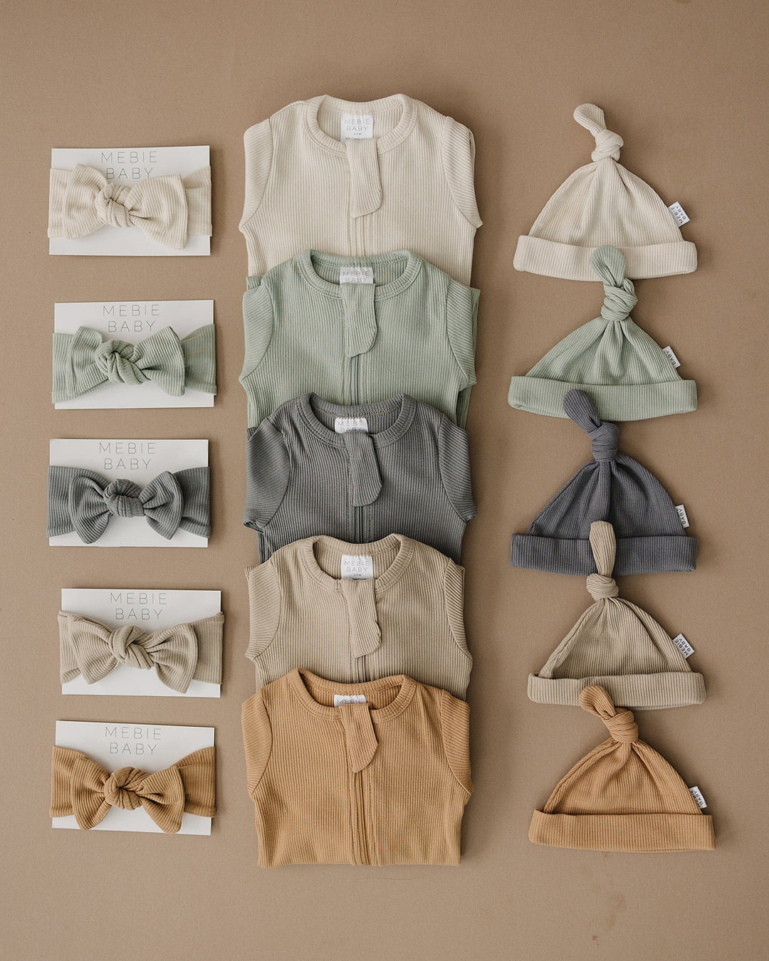 Shop baby footie pajamas at Mebie Baby, the Oatmeal Organic Cotton Ribbed Snap styled for a nursery flat lay.
