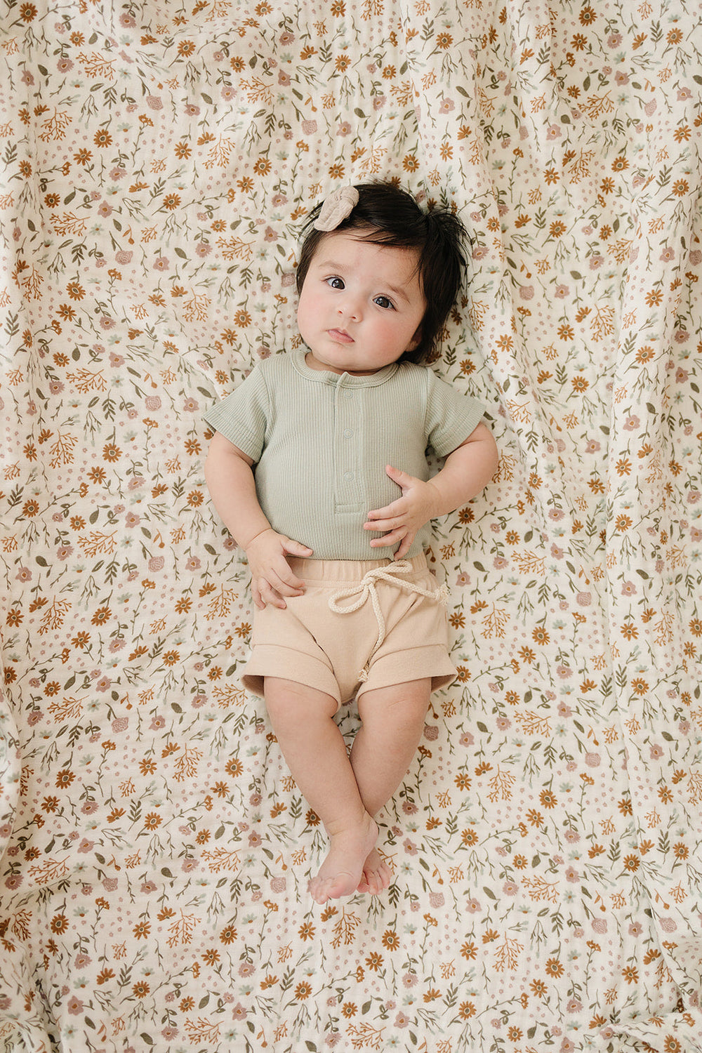 Laid flat to show the ribbed fabric, the Sage Organic Cotton Ribbed Snap Bodysuit from Mebie Baby.