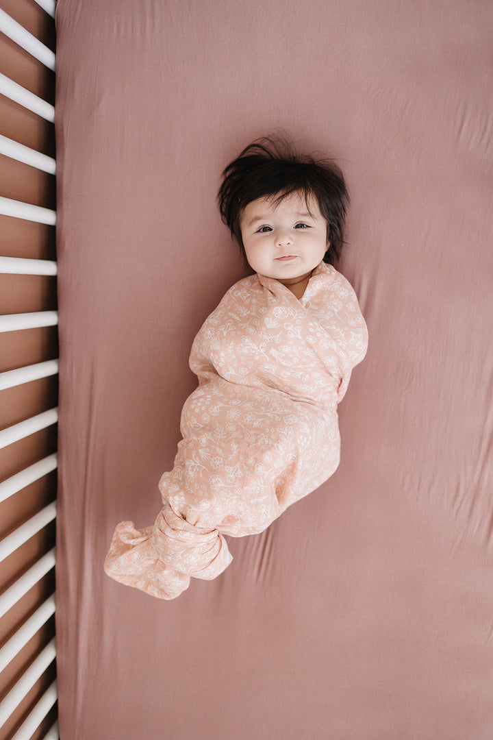 Dusty Rose Bamboo Stretch Crib Sheet styled in a calm baby room, a soft bamboo fitted crib sheet.