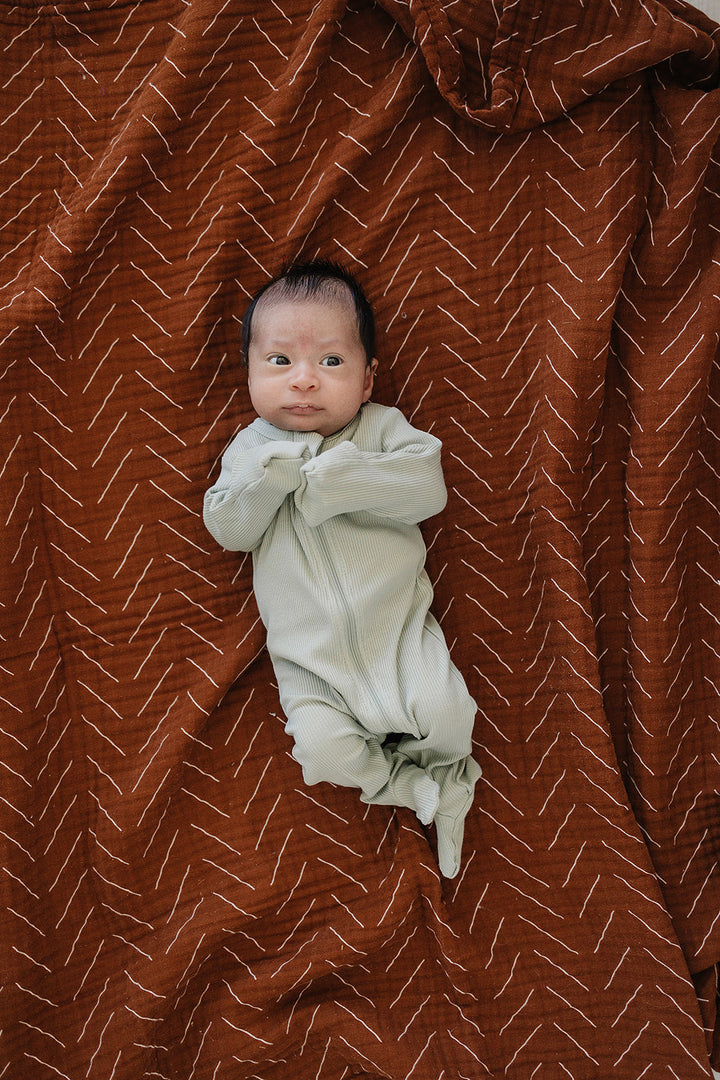 Shop baby footie pajamas at Mebie Baby, the Sage Organic Cotton Ribbed Zipper styled for a nursery flat lay.