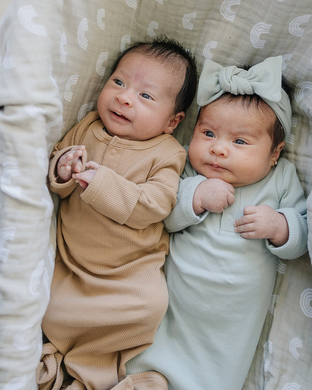 Sage Organic Cotton Ribbed Knot Gown folded neatly on a nursery shelf, an organic cotton knot gown for newborns.