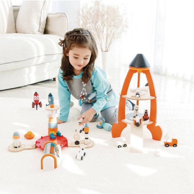 A little girl arranges spacefarer figures near the Tender Leaf Toys Cosmic Rocket Set on a cream rug