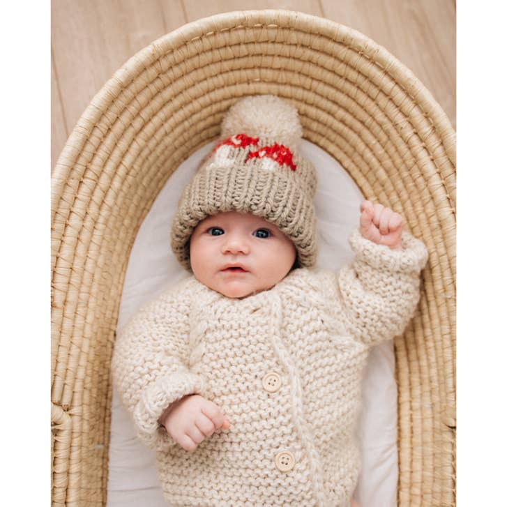 Baby wearing the Huggalugs Mushroom Hand Knit Beanie, fold-up cuff and pom pom detail