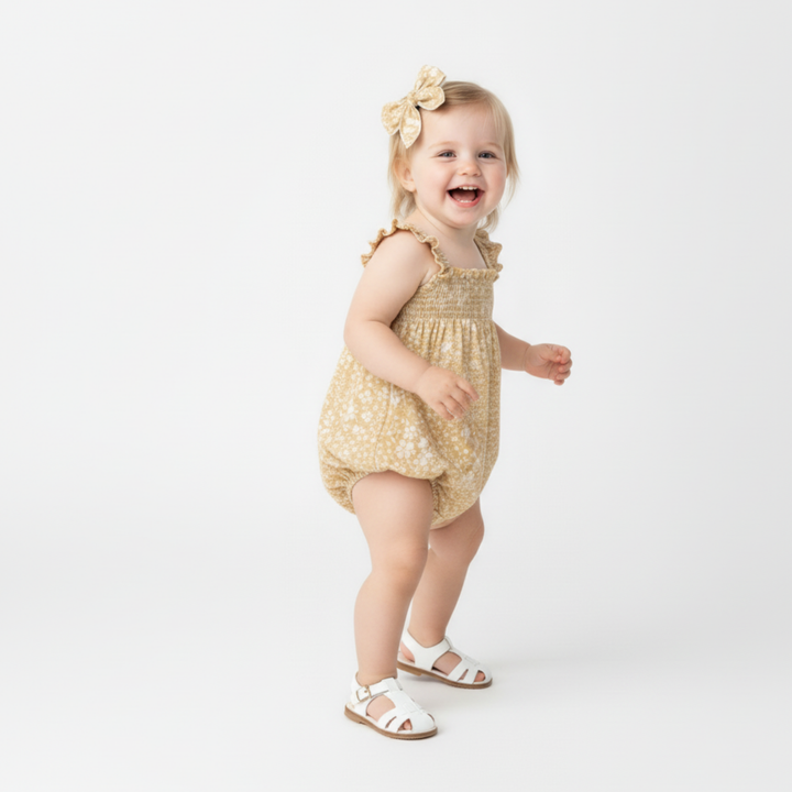 Organic ruffled baby romper in yellow blossom flat lay - MakeMake Organics summer infant outfit