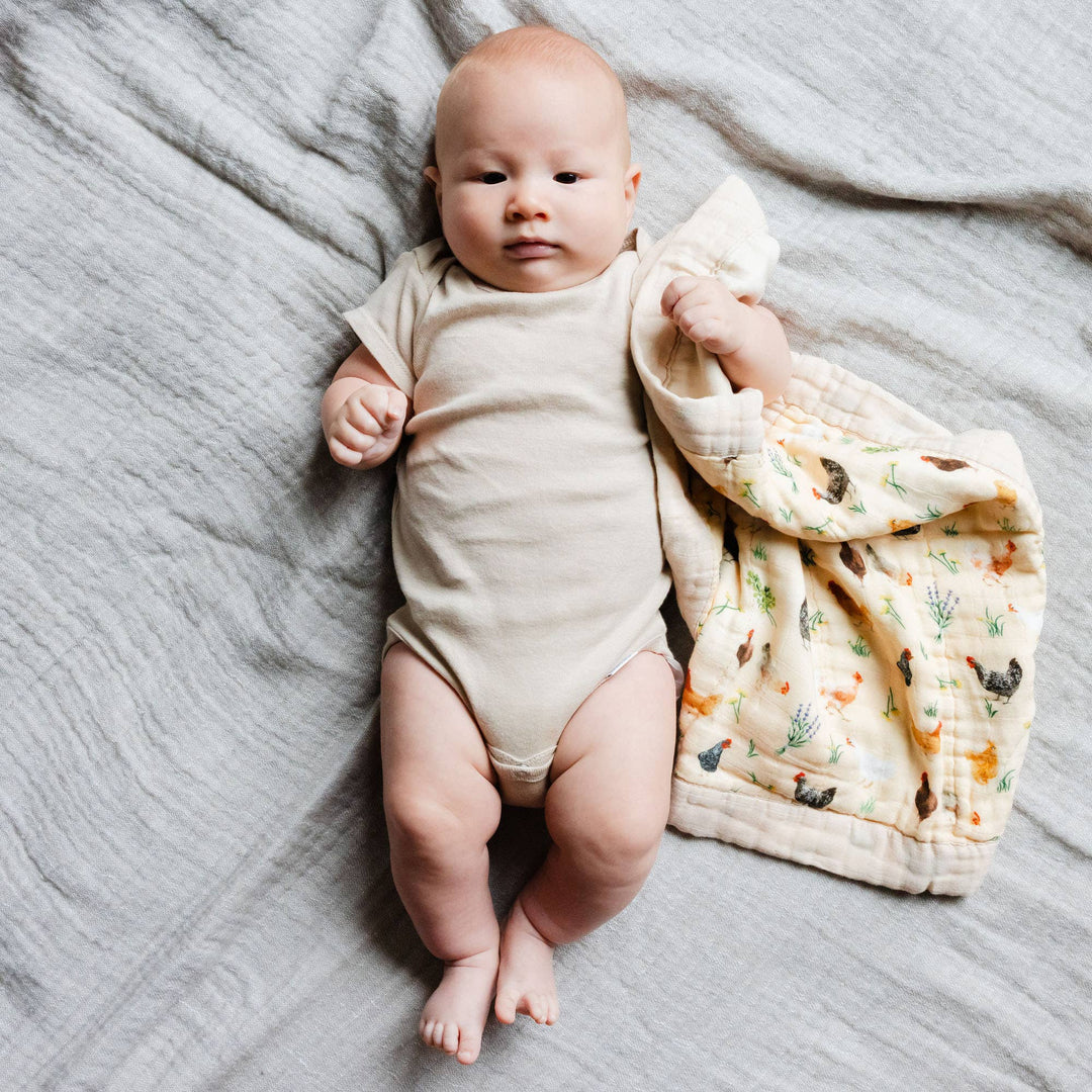 Newborn baby lying on Chicken Meadows muslin lovey blanket by 1canoe2, a soft farmhouse-print baby swaddle blanket