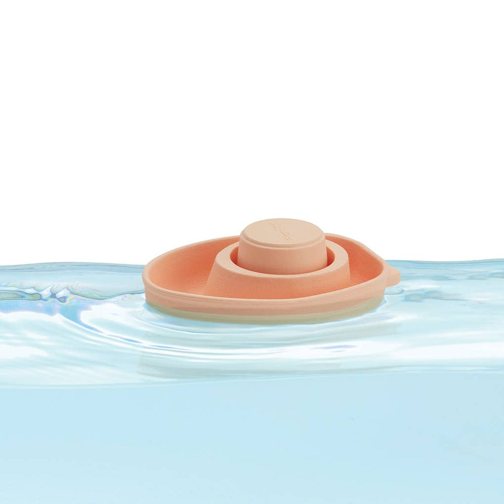 Plantoys Farm Rubber Convertible Boat in Pastel Orange floating in water, ideal baby bath toys for playful water adventures.