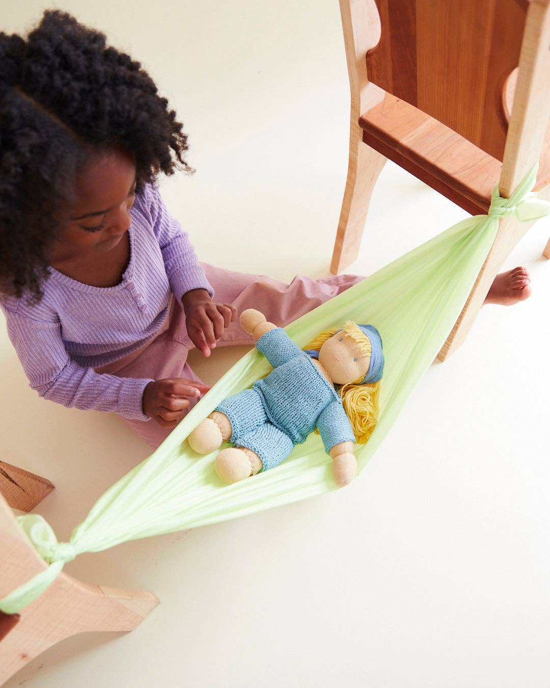Green Sarah's Silks Solid Color Playsilk used as a pretend play hammock, beloved by little ones