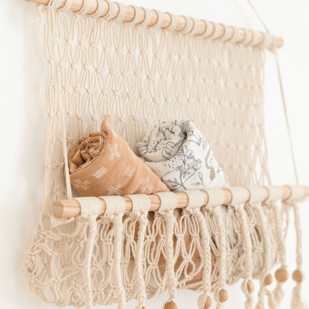 ezra cotton newborn swaddles handing on crocheted natural basket crane baby