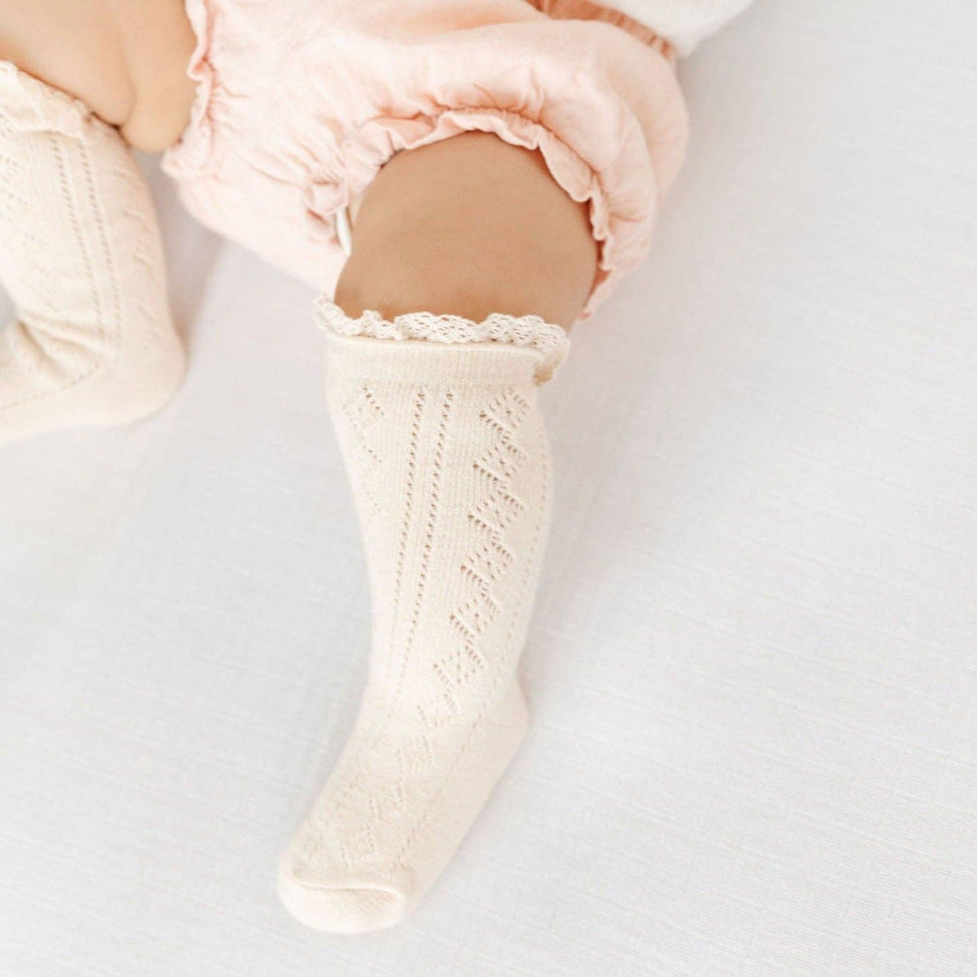 Little Stocking Co. Vanilla Fancy Lace Top Knee High Socks peek out beneath a pink tutu on a toddler