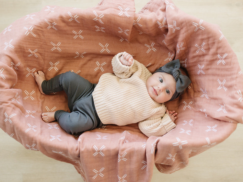 Folded on a wooden shelf, the Charcoal Organic Leggings from Mebie Baby.