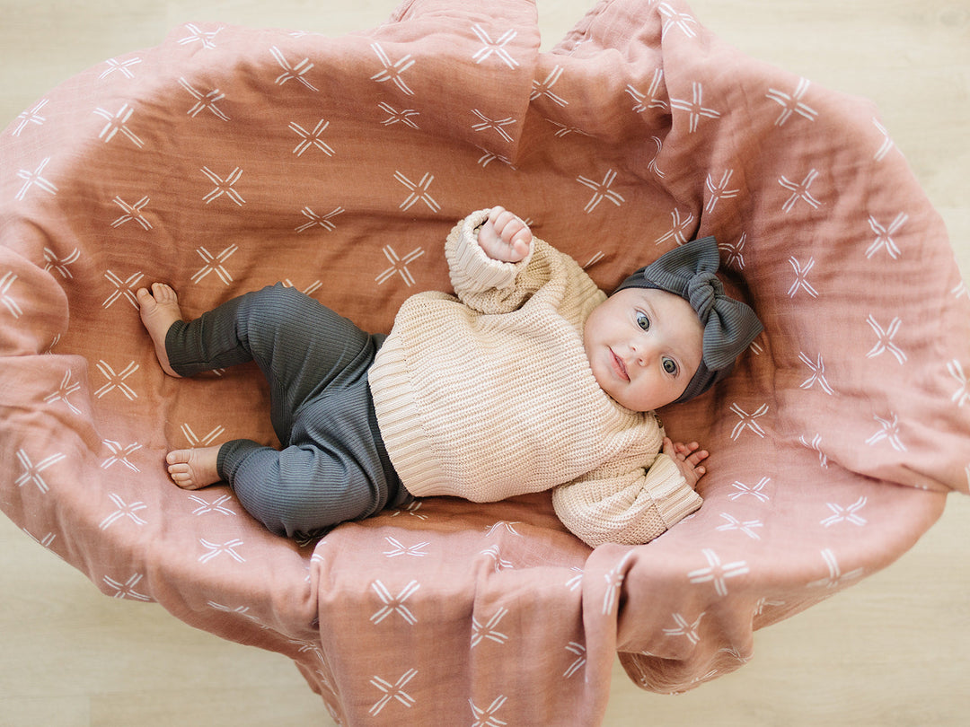 Folded on a wooden shelf, the Charcoal Organic Leggings from Mebie Baby.