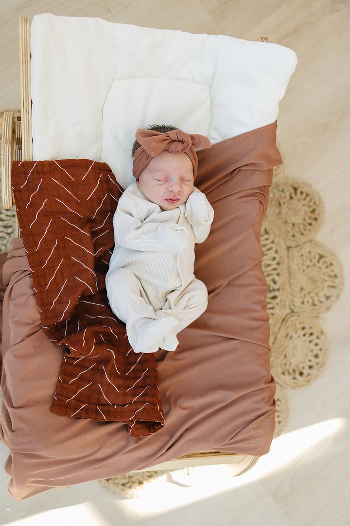 Vanilla Organic Cotton Ribbed Snap folded next to a stuffed toy, an organic cotton footie pajama for babies.