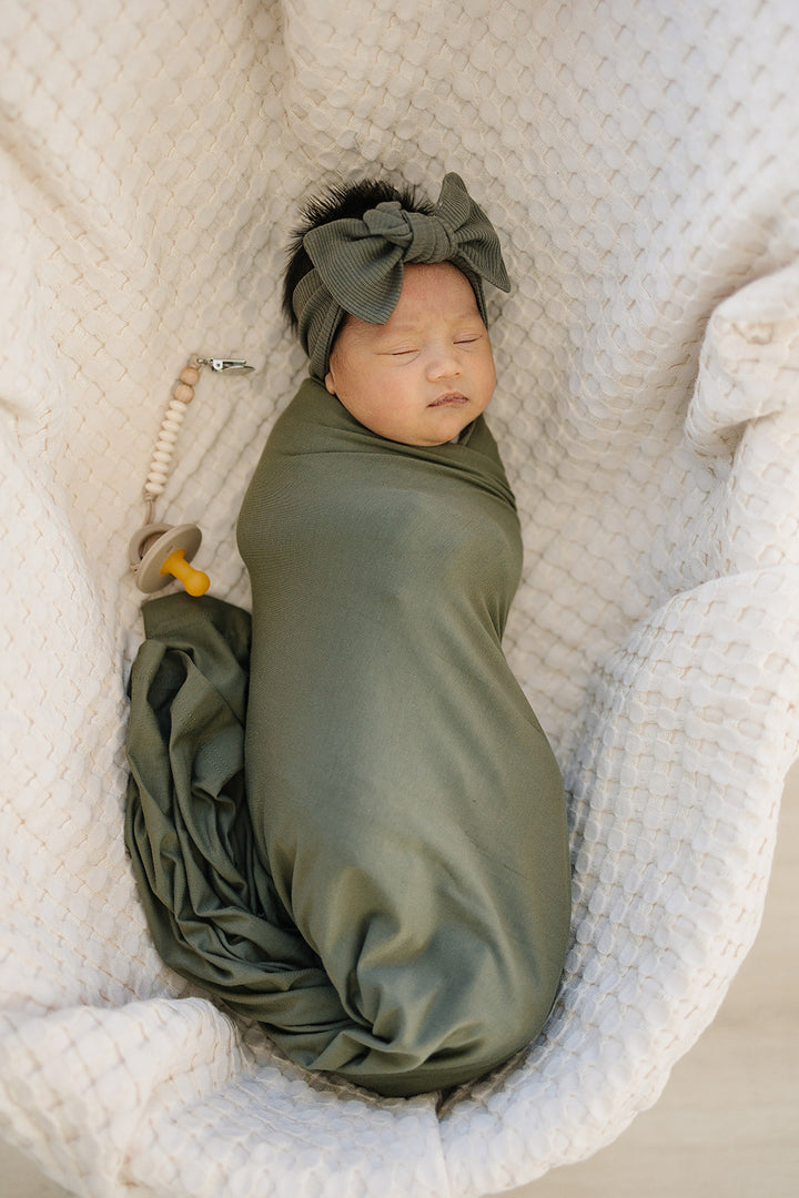 Shop swaddle blankets at Mebie Baby now, the Olive Bamboo Stretch Swaddle styled with matching nursery decor.