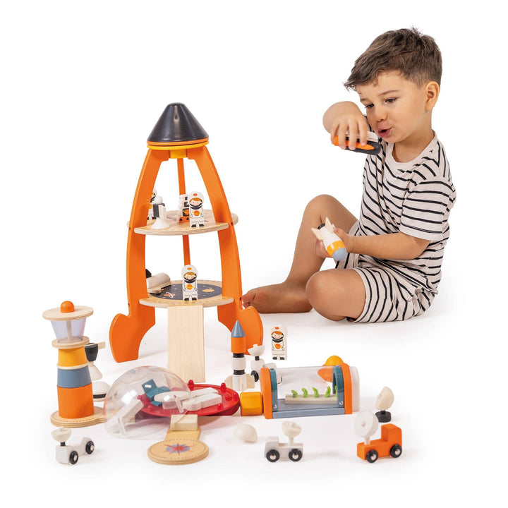 Boy in striped pajamas leans over the Tender Leaf Toys Cosmic Rocket Set for imaginative role play