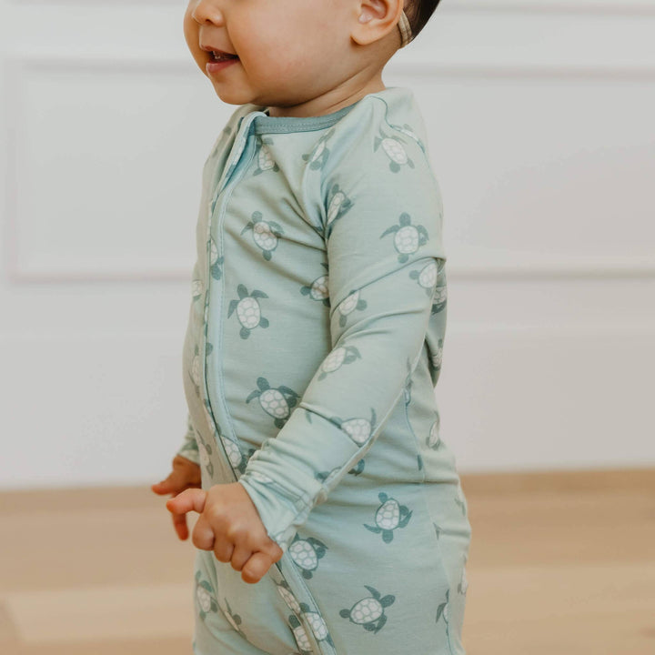 Baby standing in Copper Pearl Wade footie pajamas, soft stretch sleepwear for movement and toddler comfort