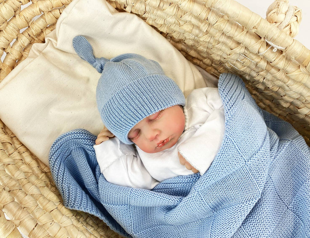 Baby napping in a Moses basket in a light blue ALIAP Merino Wool Top Knot Baby Beanie, soft knitwear for fall and winter