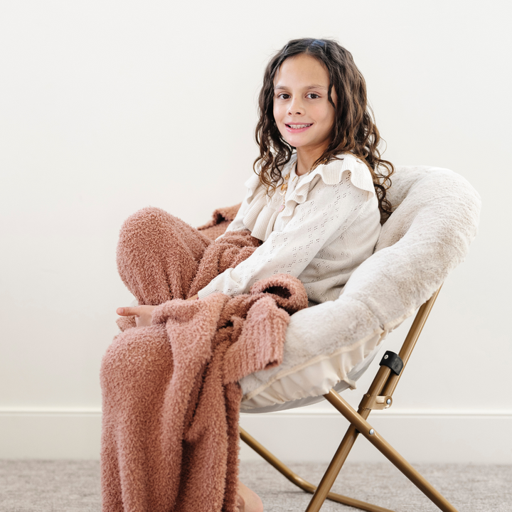 Kids enjoy relaxing in Buff Saranoni Saucer Chair, a soft and colorful kids lounger.