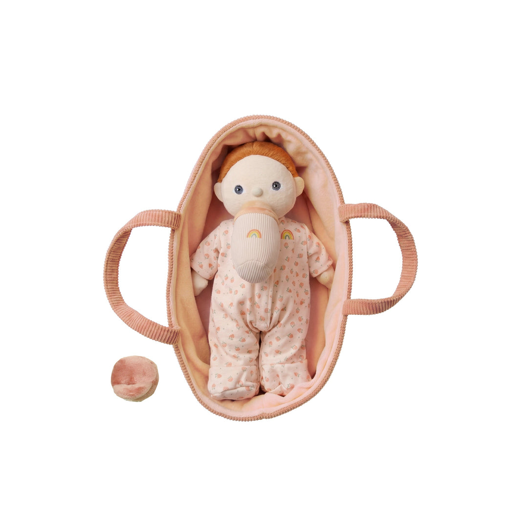 Dinkum Dolls Binky Dinky Pickle baby doll resting in a peach bassinet with magnetic pacifier