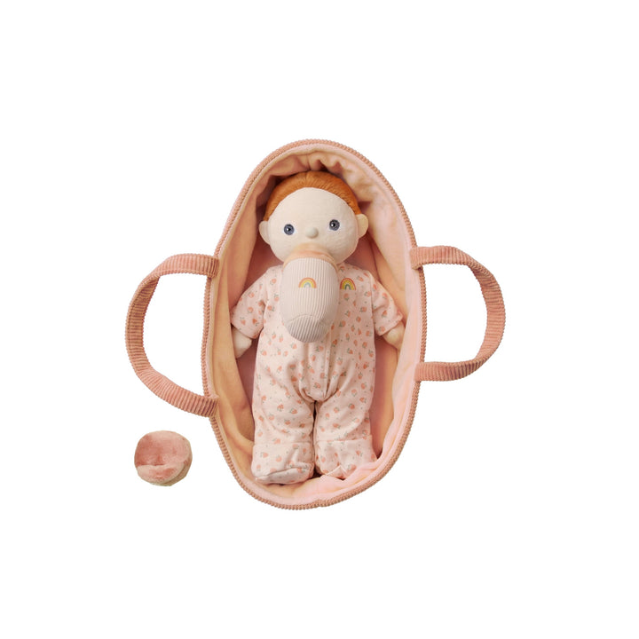 Dinkum Dolls Binky Dinky Pickle baby doll resting in a peach bassinet with magnetic pacifier