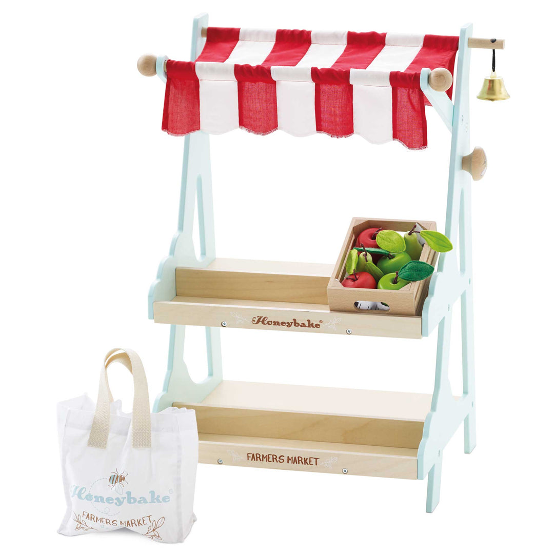 Wooden market stall with a red and white striped canopy, brass bell, and canvas shopping bag from Le Toy Van