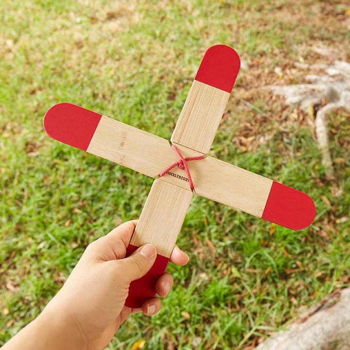Child holding Huckleberry Pocket Boomerang outdoor toy in grassy area