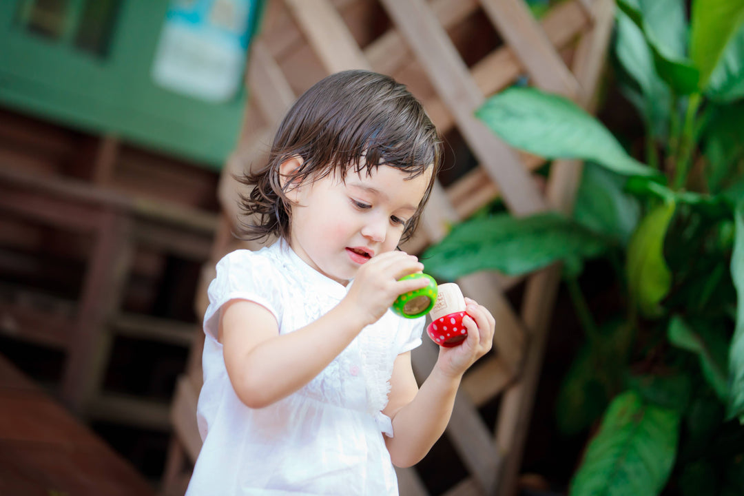 Child holding PlanToys wooden mushroom kaleidoscope educational visual toy