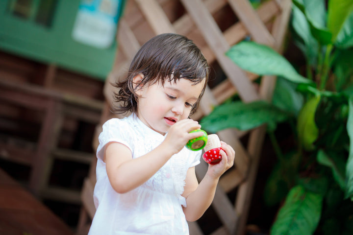Child holding PlanToys wooden mushroom kaleidoscope educational visual toy