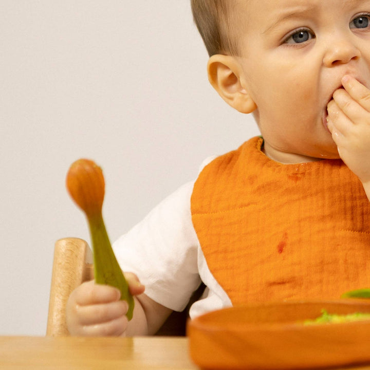 Baby using Oil & Carol spoon at mealtime, baby led weaning utensil for first foods, toddler feeding, and self feeding practice