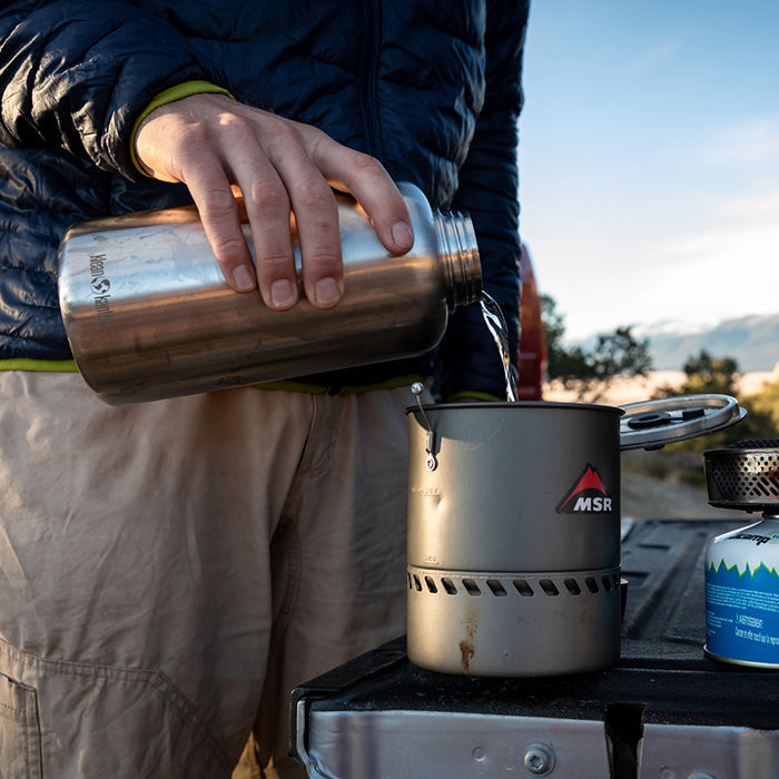 Camping setup showing Klean Kanteen 64oz Wide Water Bottle in Black, dishwasher safe and temperature controlled for hot or cold drinks.