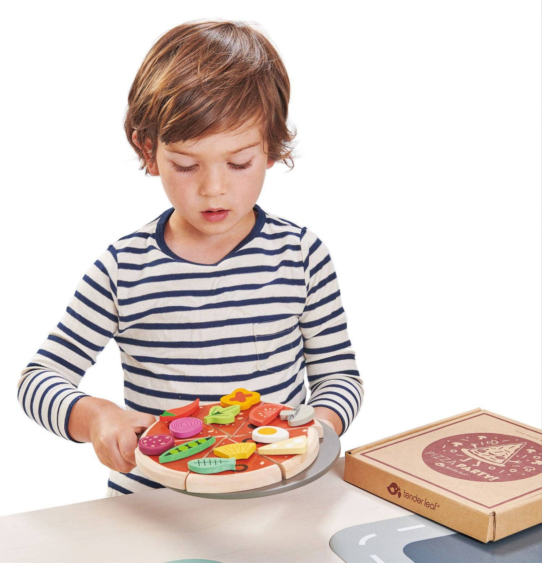 Boy plays with a pizza slice at the table using his Tender Leaf Toys Pizza Party
