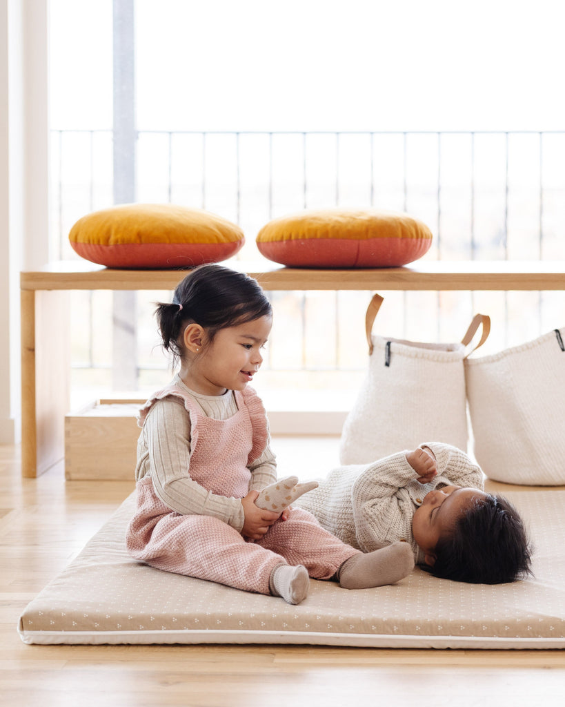 Two kids playing on the Piccalio waterproof and machine washable play mat.