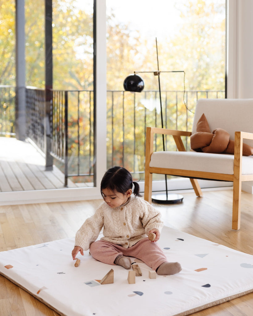 Little girl stacking blocks on the Piccalio play mat.