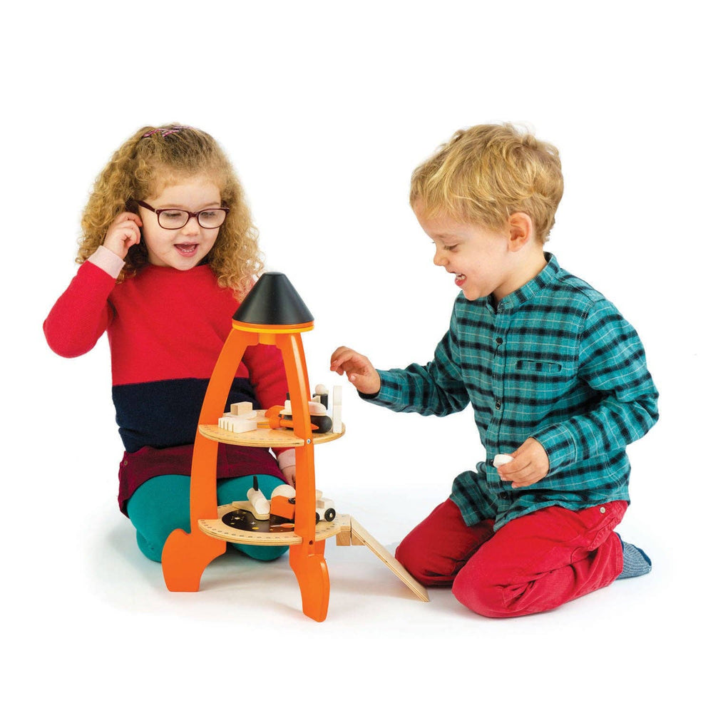 Two kids in cozy pajamas share pretend play time with the Cosmic Rocket Set from Tender Leaf Toys