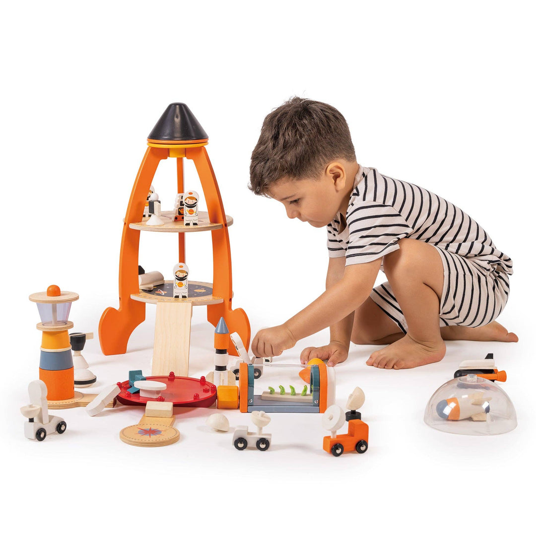 A young boy sets up the orbiter and moon rover pieces from the Cosmic Rocket Set on the floor