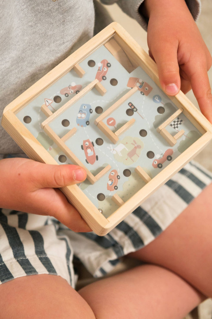 A child's hand holds the car themed Mini Wooden Labyrinth by Egmont during quiet playtime