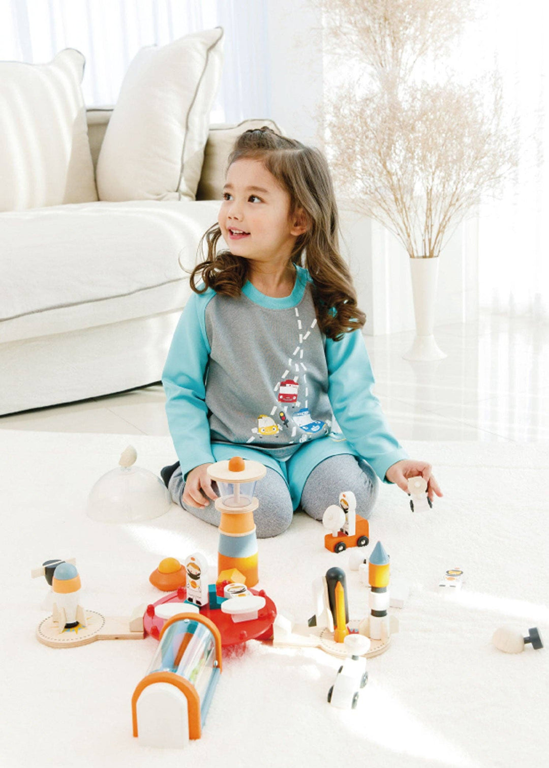 Toddler girl enjoys imaginative space play with the Cosmic Rocket Set beside a bright living room window