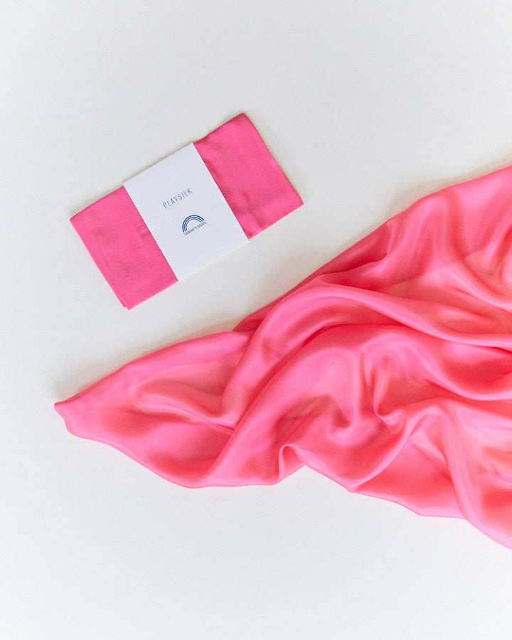 Flat lay of a pink Sarah's Silks Solid Color Playsilk, adored by kids everywhere