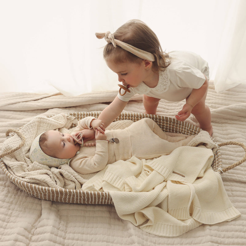 Two children in a basket with the Bleu La La Heritage Knit 100% Organic Cotton Swaddle Baby Blanket